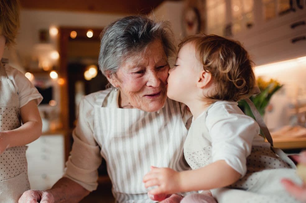 małe dziecko całujące babcię w policzek