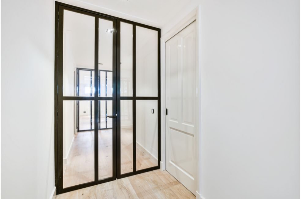 nowoczesne, przeszklone drzwi z czarnymi ramkami w białym pomieszczeniu