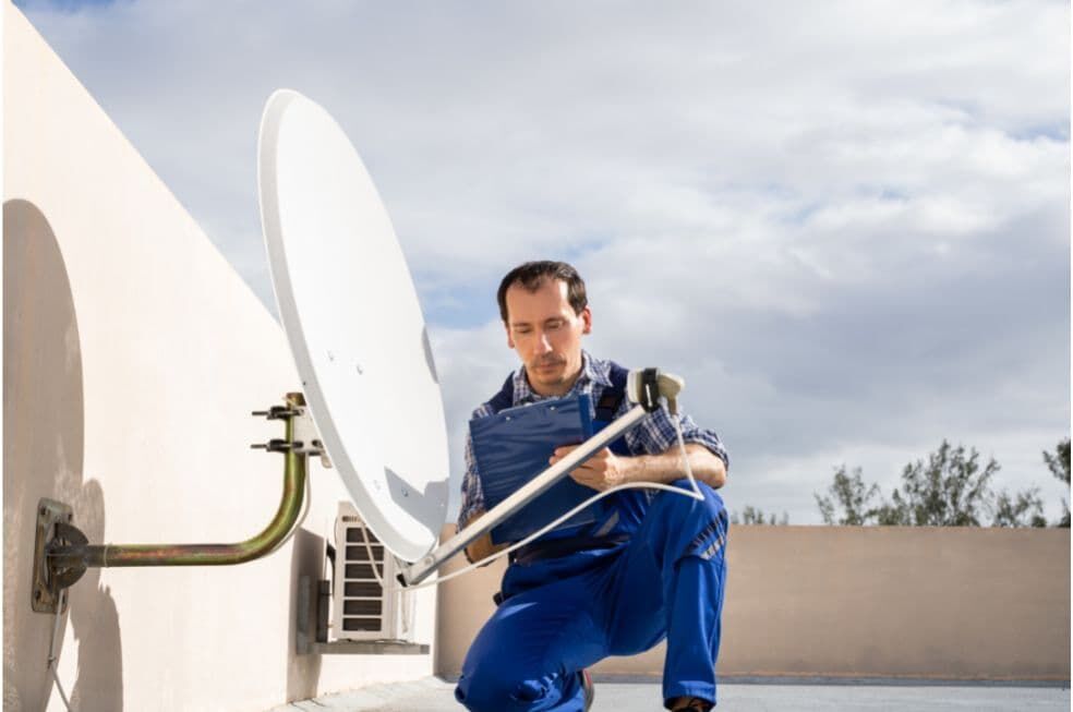 mężczyzna sprawdzający antenę satelitarną