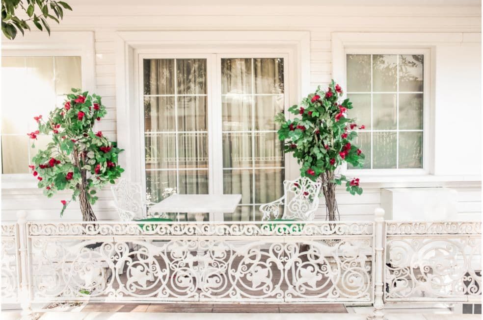 piękny zdobiony biały balkon z dwoma krzewami róży