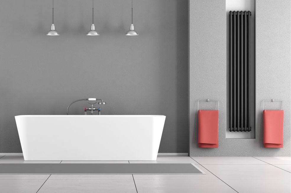 nowoczesna szara łazienka z białą wanną i czarnym, wysokim grzejnikiem na ścianie