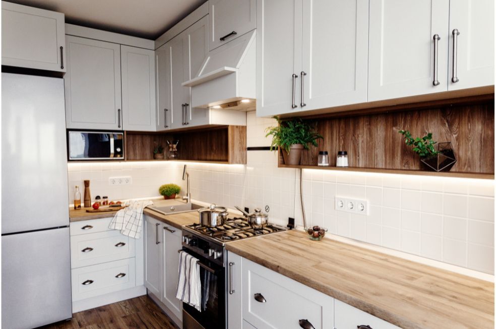 białe meble w kuchni w stylu klasycznym z białymi kafelkami na ścianie i drewnianymi panelami