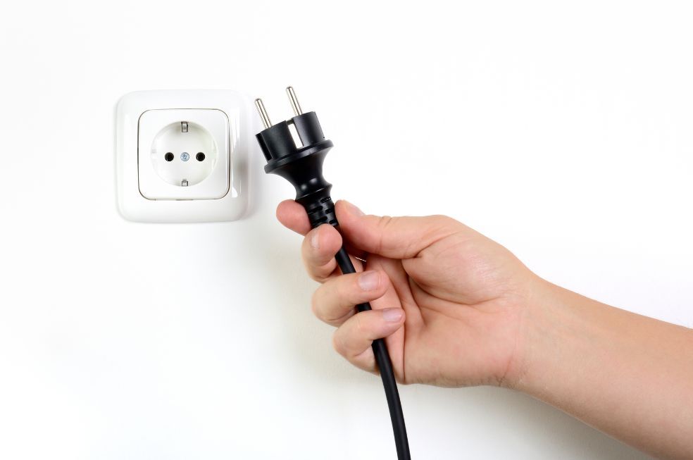 osobą trzymająca kabel z wtyczką koło gniazdka