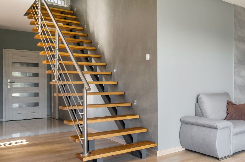schody wewnętrzne drewniane z metalową poręczą w szarym salonie
