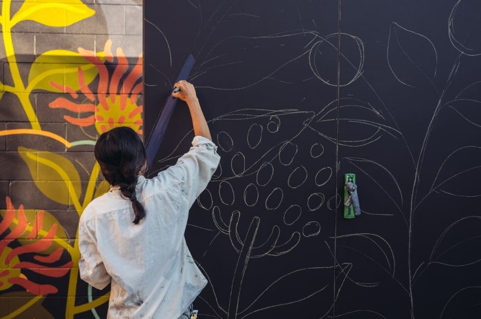 kobieta malująca mural na ścianie