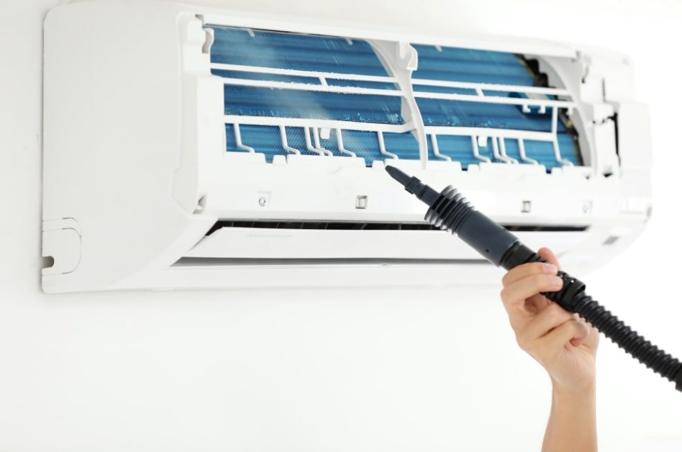 mężczyzna czyszczący klimatyzację specjalnym urządzeniem