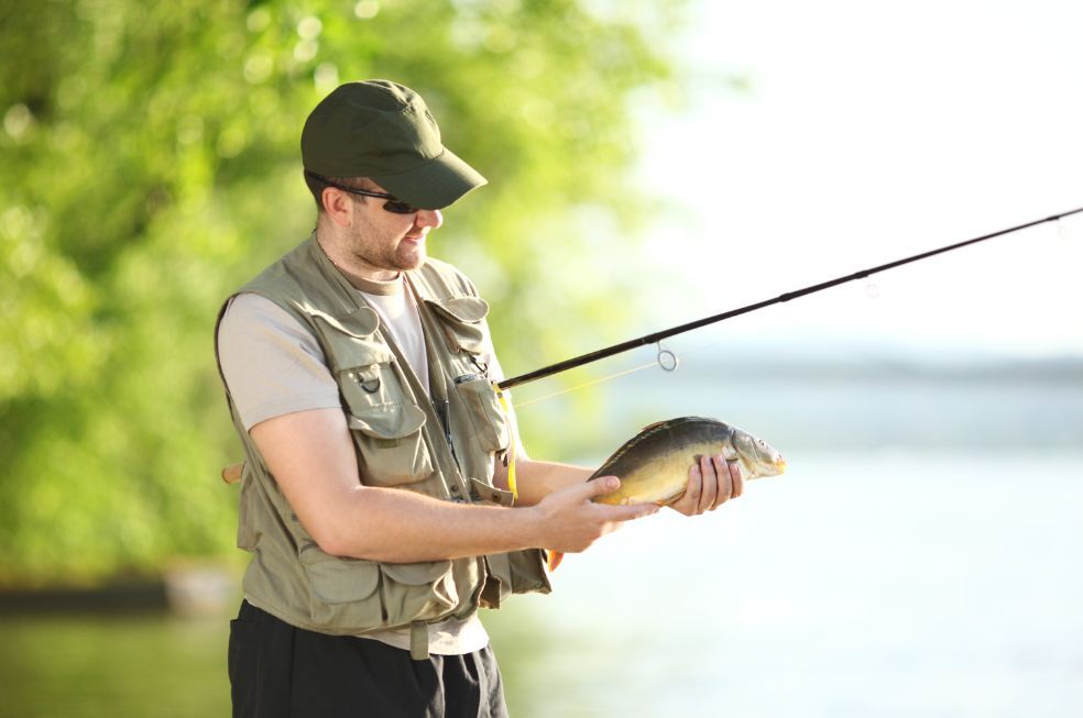 wędkarz wyciągający złowioną rybę z rzeki