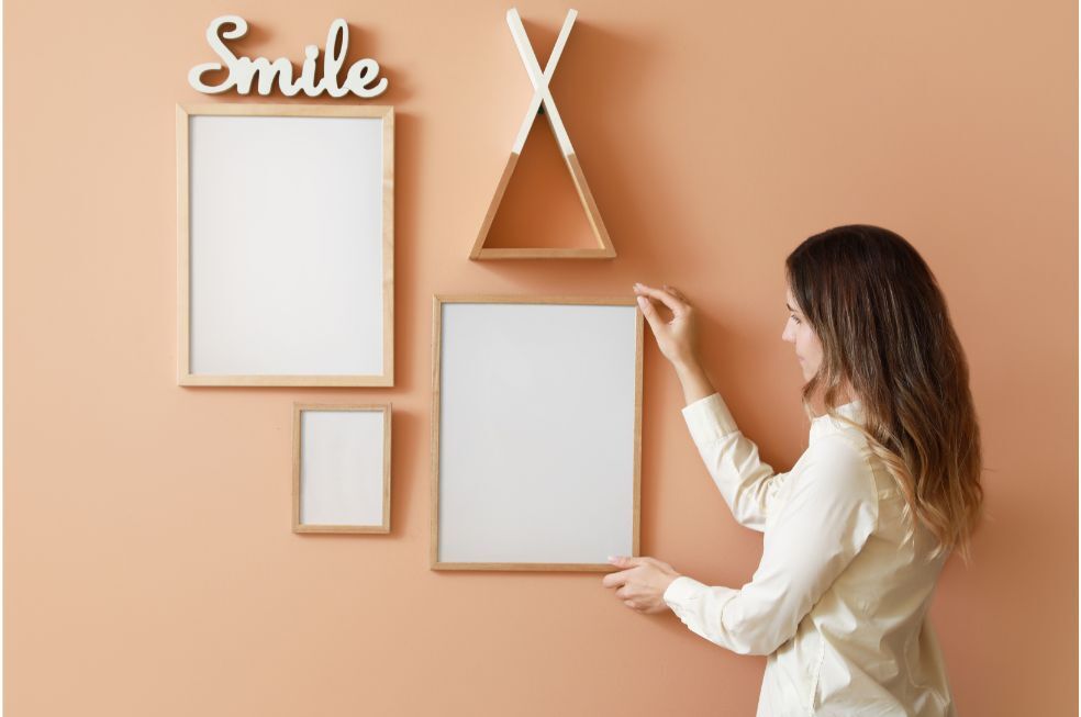 Kobieta wieszająca ramkę na zdjęcia na ścianie