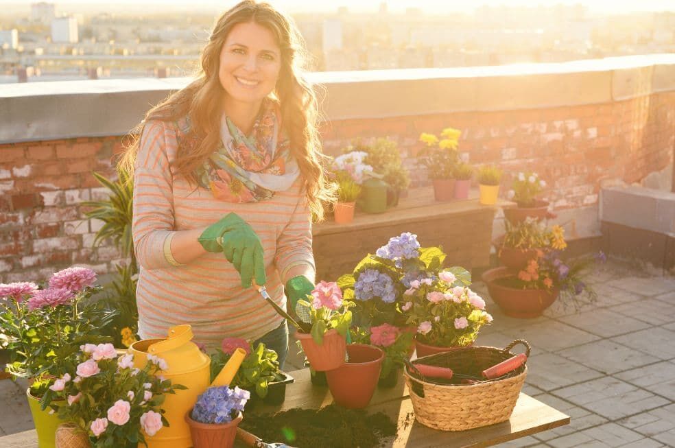 kobieta sadząca kwiaty na tarasie na dachu