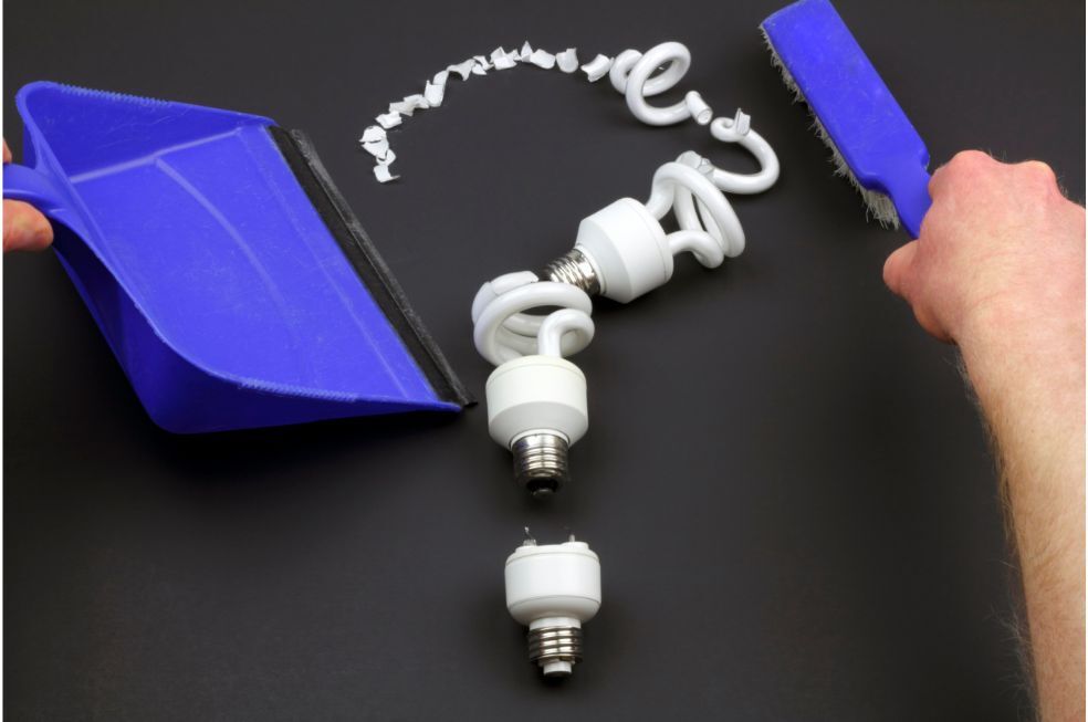 mężczyzna sprzątający rozbitą żarówkę