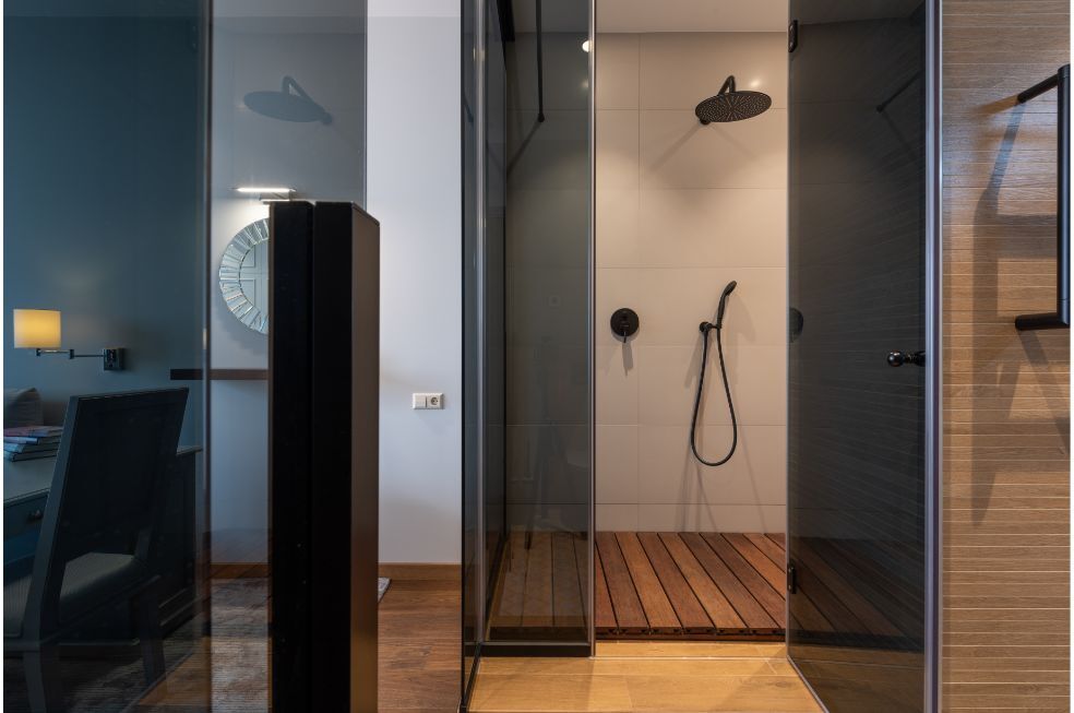 nowoczesna kabina prysznicowa z czarną szybką i drewnianym podestem