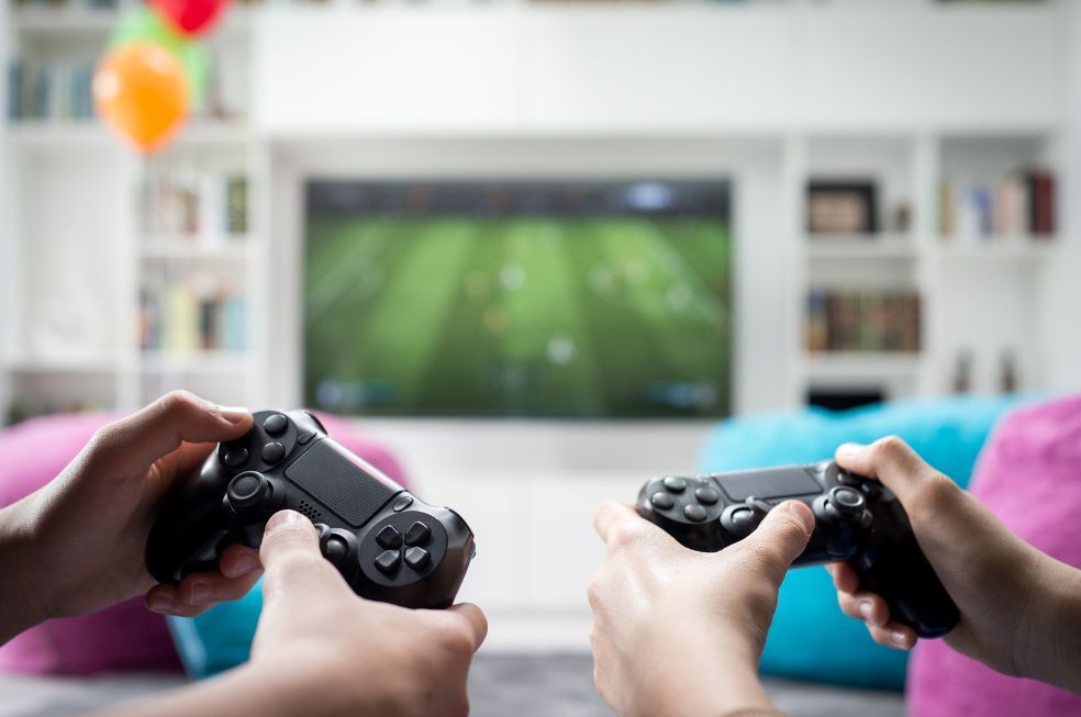 dwie osoby grające na konsoli przed telewizorem