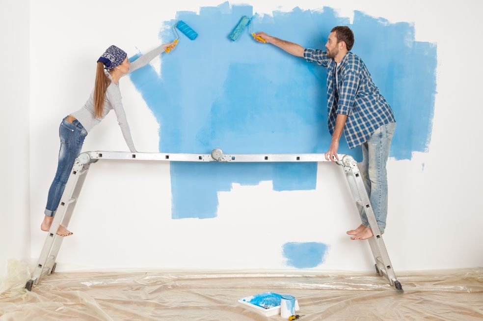 kobieta i mężczyzna malują ściany w pokoju na niebiesko