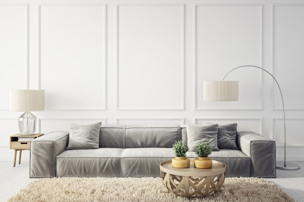salon w jasnych kolorach z szarą kanapą i dwiema stojącymi lampami z białym, okrągłym kloszem