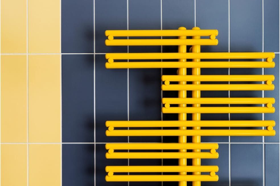 designerski żółty grzejnik na płytkach