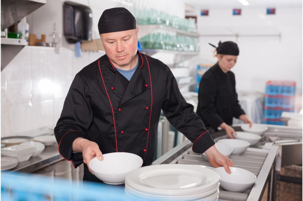 pracownik kuchni układający umyte naczynia